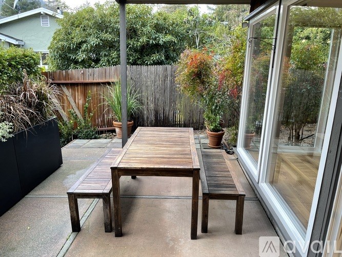 A wooden table and bench are on a patio.