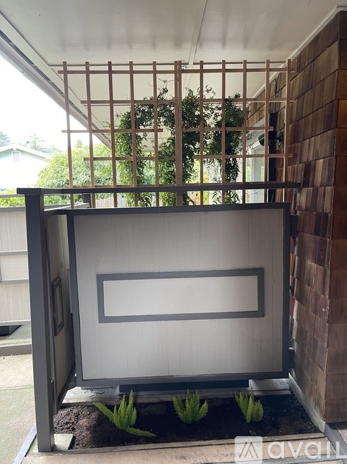 A small garden with a wooden trellis and a white rectangular structure.