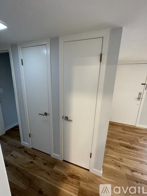 Three white doors in a row on a wood floor.