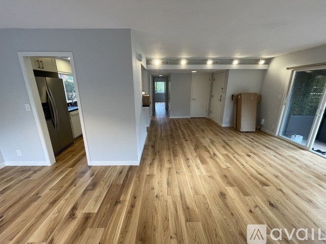 A spacious room with wooden flooring and white walls.