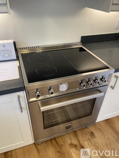 A modern stainless steel oven with a digital display and control knobs is installed in a kitchen.