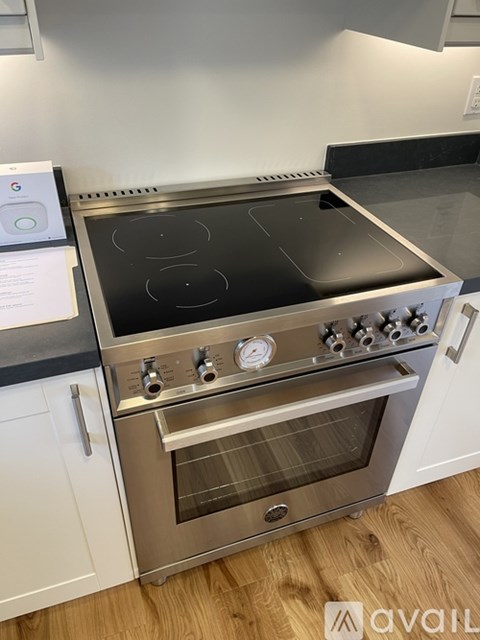 A modern stainless steel oven with a digital display and control knobs is installed in a kitchen.