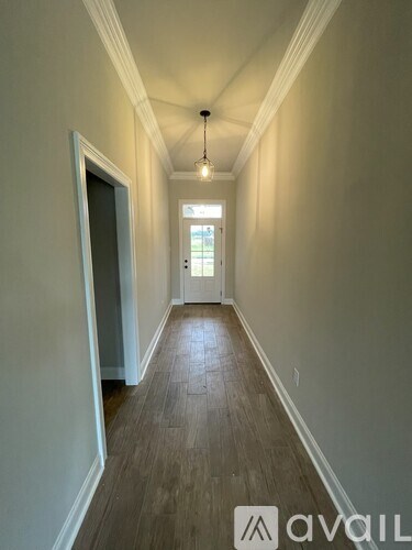 A long hallway with wood floors and white walls.