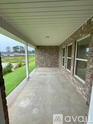 A covered porch with a white ceiling and brick columns.