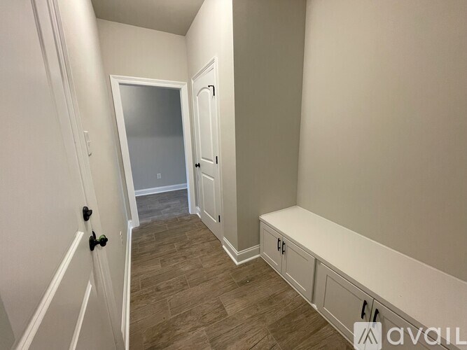 A hallway with a bench and a door at the end.