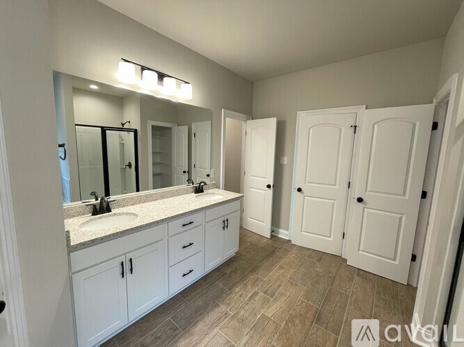 A bathroom with a vanity, sink, mirror, and wood flooring.
