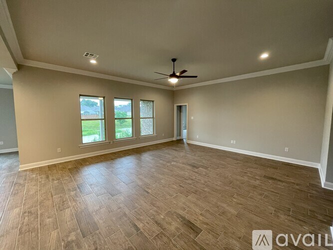 A spacious room with a ceiling fan and wooden flooring.