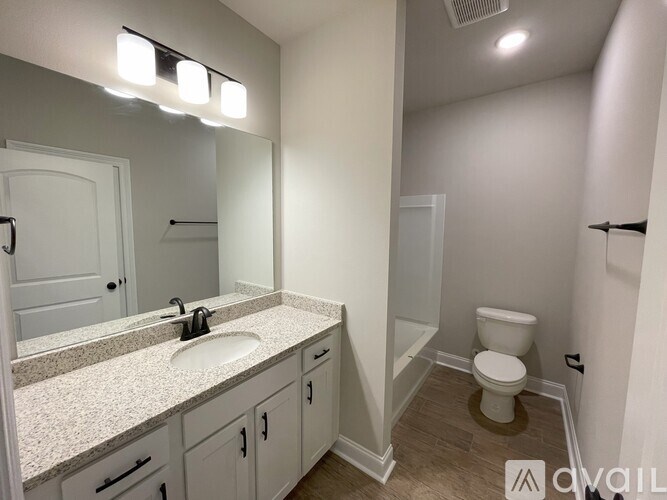 A bathroom with a sink, toilet, and mirror.