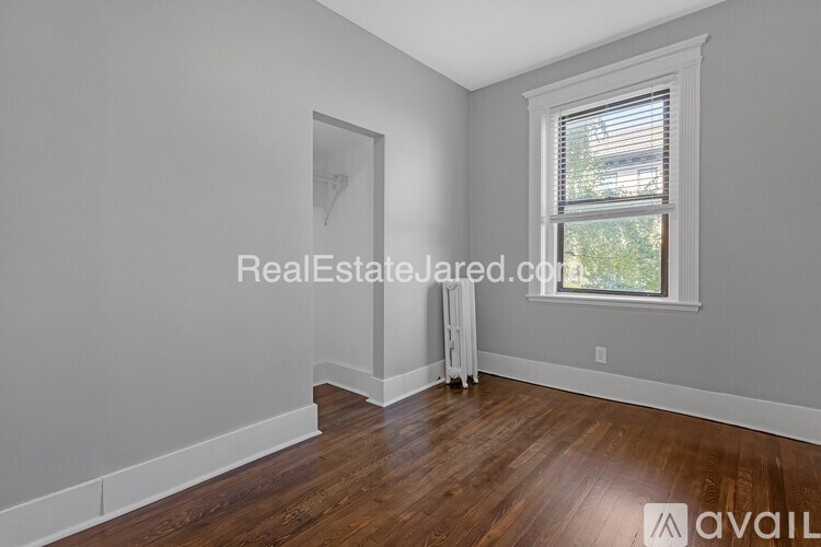 A room with wooden floors and a window with blinds.