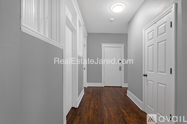 A hallway with white doors and a wooden floor.