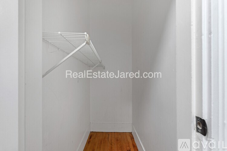 A white shelf is in the corner of a white room.