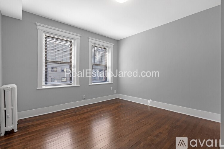 A room with wooden floors and two windows.