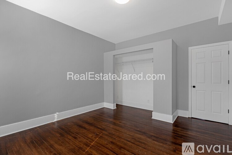 A room with wooden floors and white walls, with a doorway leading to another room.