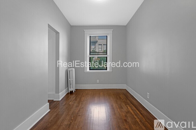 A room with wooden floors and a window showing a cityscape.