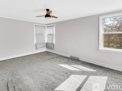 A room with a ceiling fan and a window with a view of trees outside.