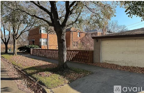 A tree in front of a house with a garage.