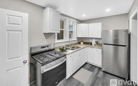A kitchen with white cabinets and a stainless steel refrigerator.