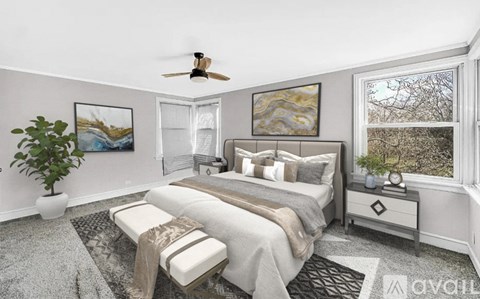 A bedroom with a bed, a ceiling fan, and a window with a view of trees.