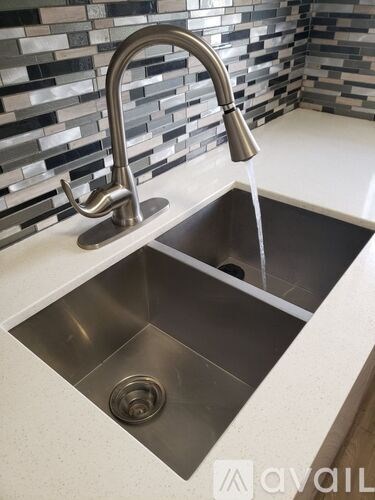A modern kitchen sink with a chrome faucet and a drain.