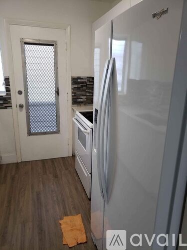 A white refrigerator stands in a kitchen with a door open.