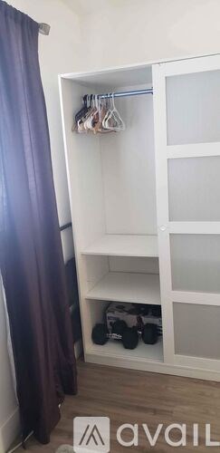 A white closet with clothes hanging on hangers.