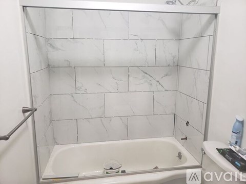 A white marble tiled bathroom with a white bathtub and a towel rack.