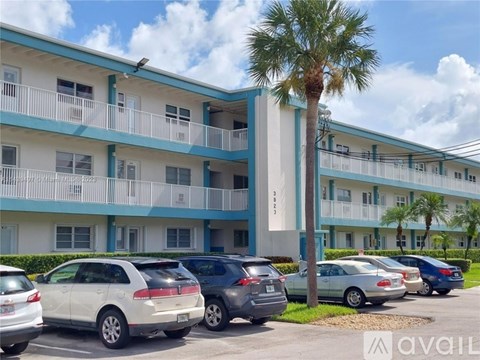 Cars parked in front of a blue and white building with a palm tree.