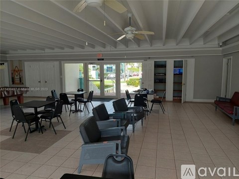 A spacious room with tables and chairs and a ceiling fan.