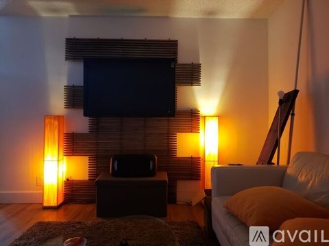 A living room with a television, a couch, and two lamps.