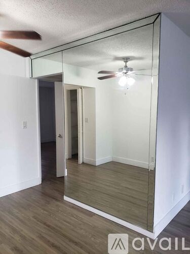 A room with a mirror and a ceiling fan.