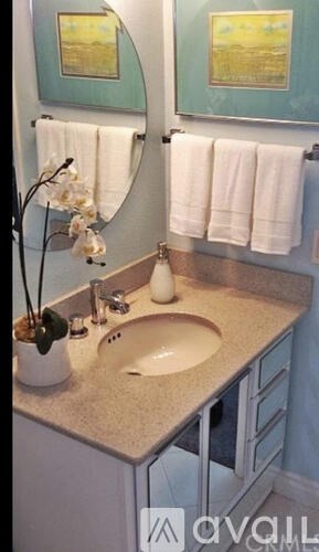 A bathroom with a sink, mirror, and towel rack.