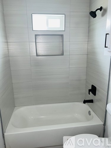 A white bathroom with a tub and a window.