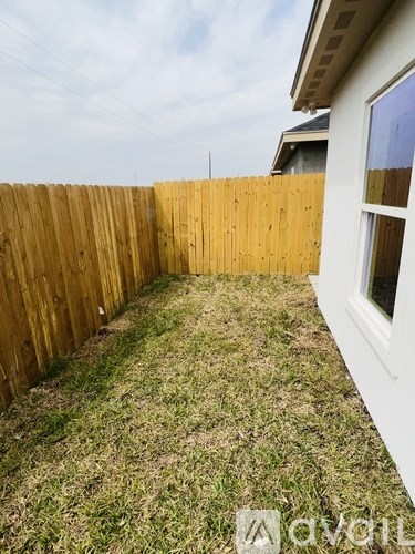 A backyard with a wooden fence and a white house.