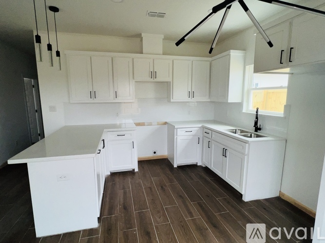 A kitchen with white cabinets and a wooden floor.