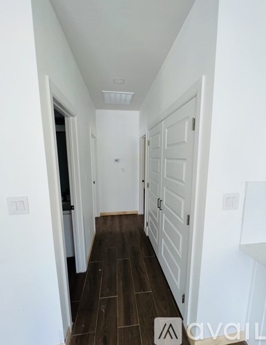 A long hallway with white doors and a brown floor.