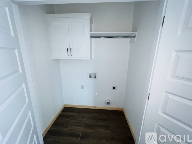 A small, empty room with white walls and a wooden floor.