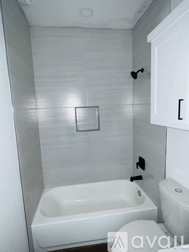 A white bathroom with a tub, toilet and sink.