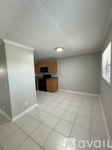 A room with white tile flooring and a window with blinds.