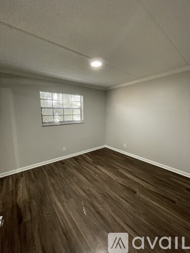 A room with wooden flooring and a window.
