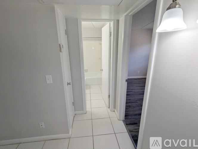 A hallway with white walls and tiled flooring.