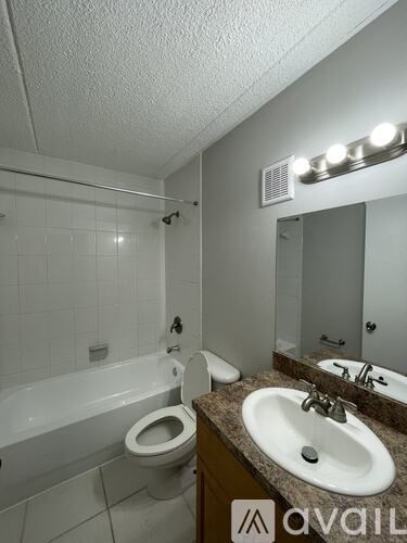 A bathroom with a toilet, sink, and mirror.