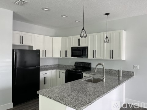 A kitchen with black appliances and white cabinets.