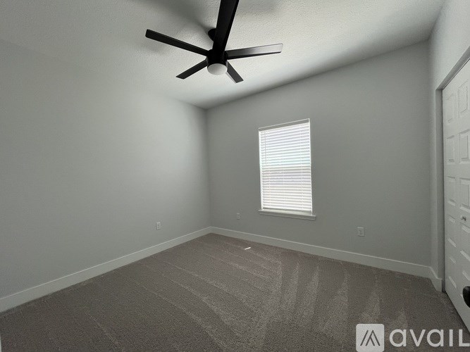 A room with a ceiling fan and a window with blinds.