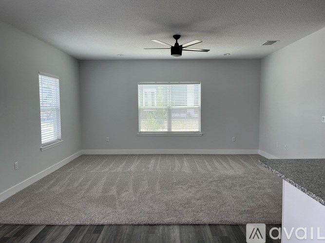 A spacious room with a ceiling fan and carpeted floor.