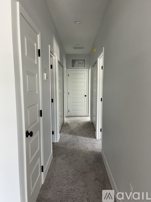 A hallway with white doors and carpeted floor.