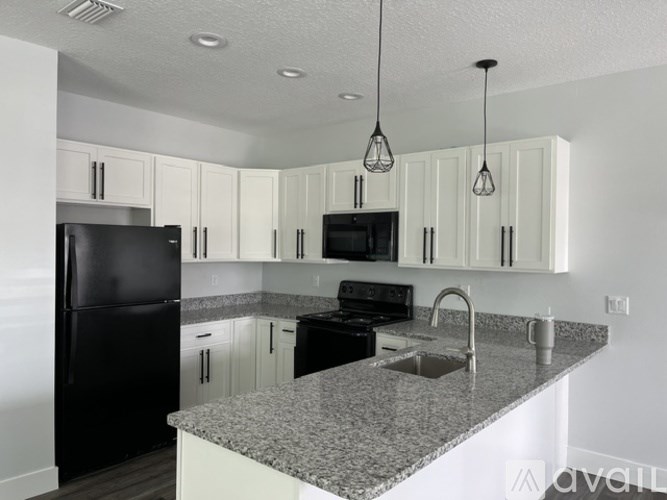 A kitchen with black appliances and white cabinets.