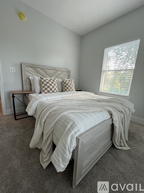 A bedroom with a large bed and a window with blinds.