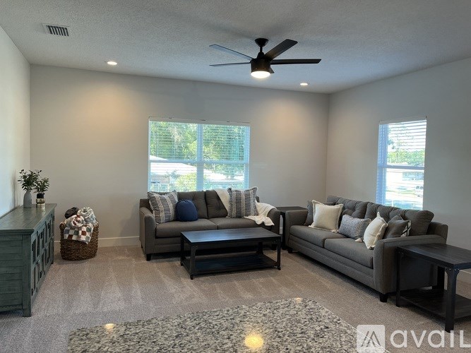 A living room with a grey couch, a black coffee table, and a ceiling fan.