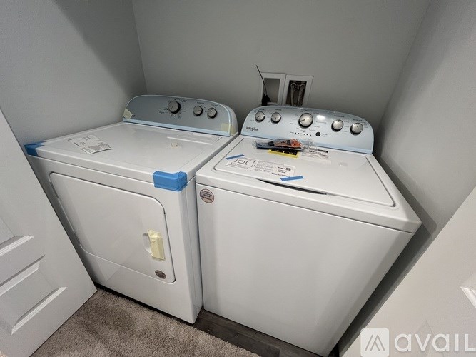 Two white front loading washing machines in a small laundry room.