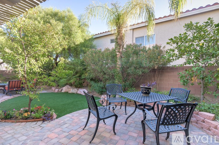 A patio with a table and chairs surrounded by greenery.